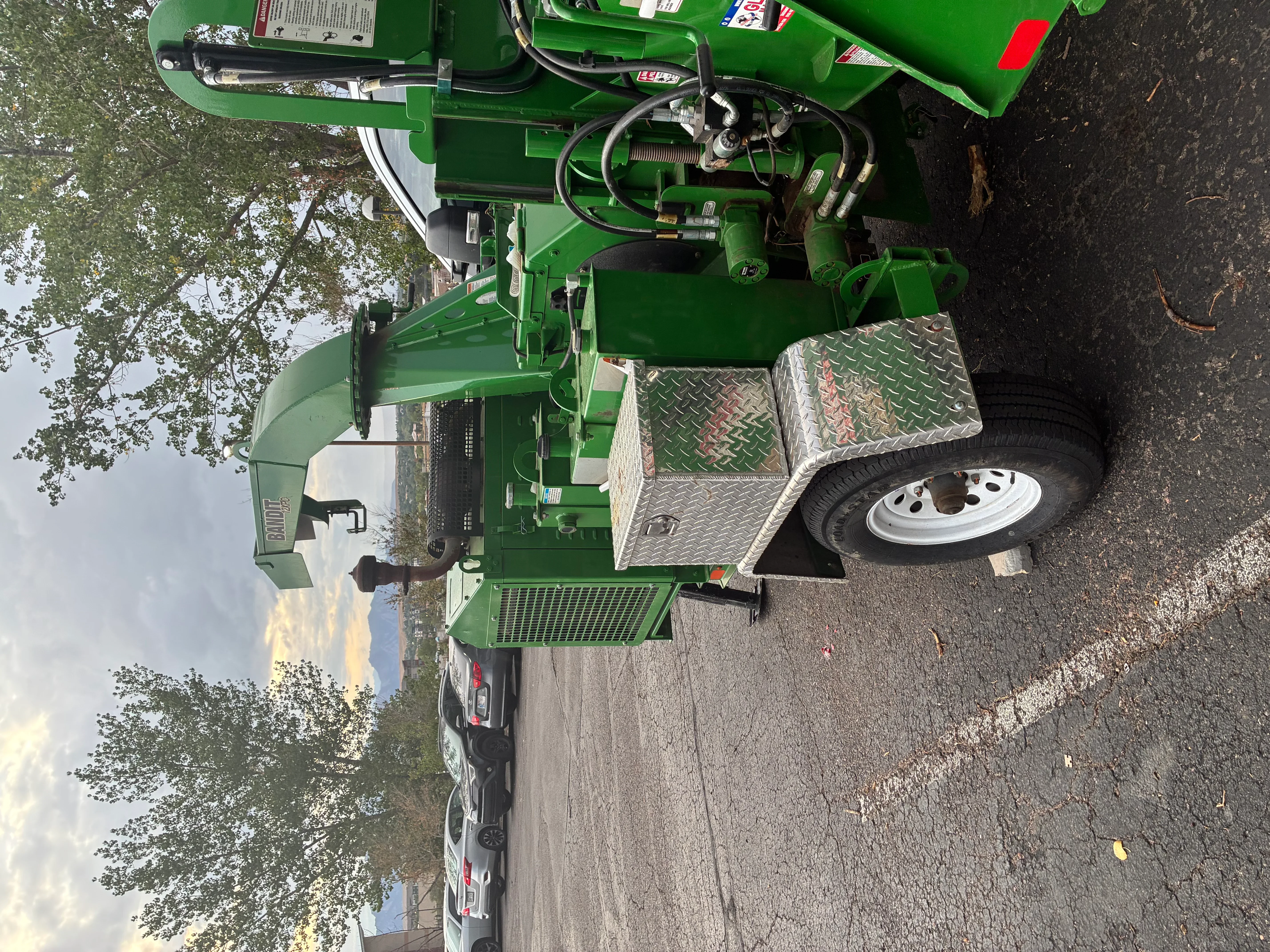 Green hydraulic stump grinder on trailer with steel platform and controls