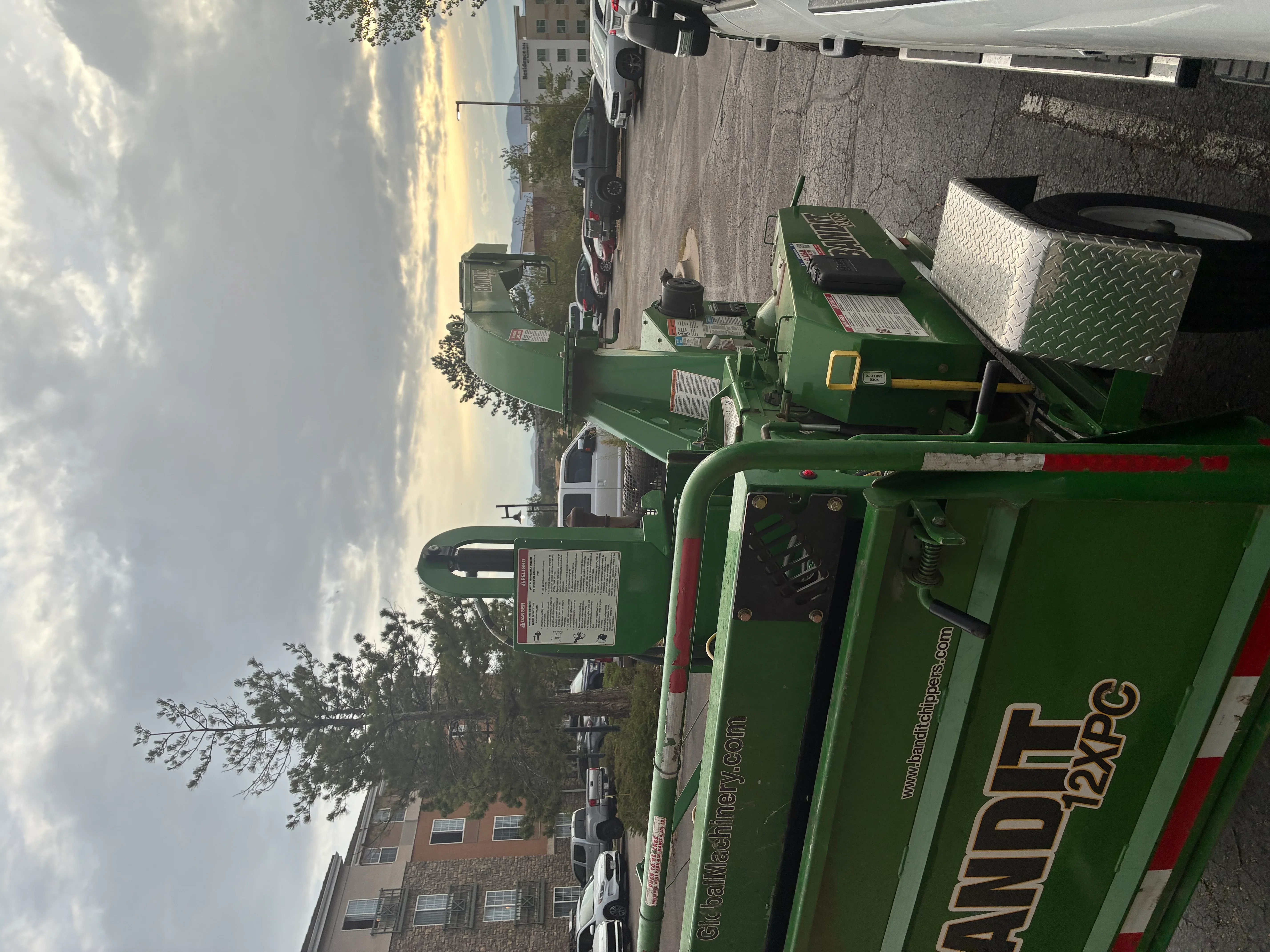 Green stump grinder with diamond-plate platform and hydraulic controls on city street