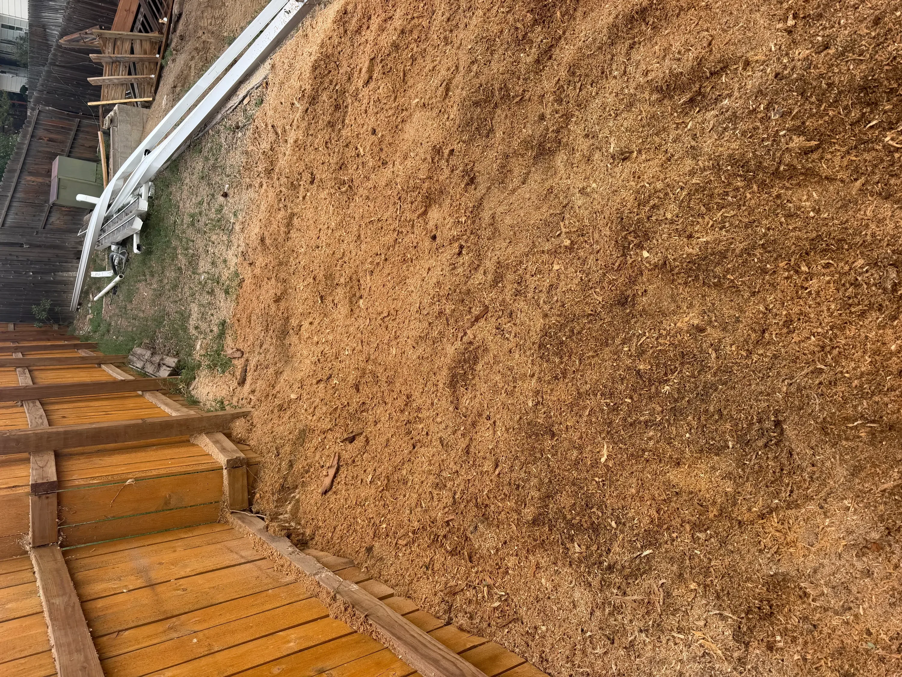 Graded dirt lot with wooden retaining timbers and white gutter system along building edge