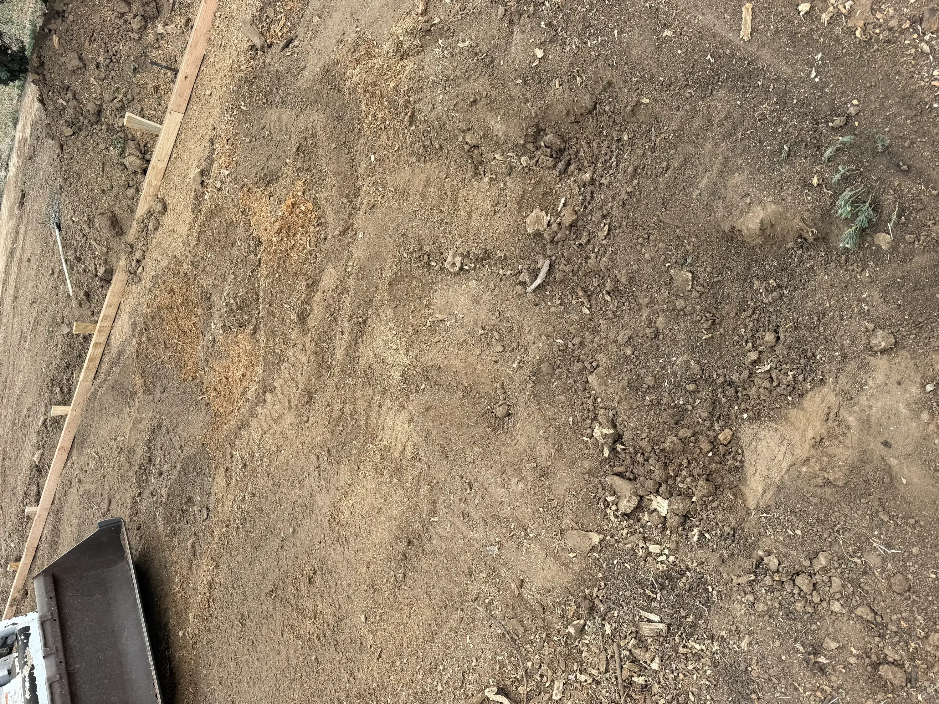 Cleared dirt lot with compacted soil and wooden grade guides for site preparation