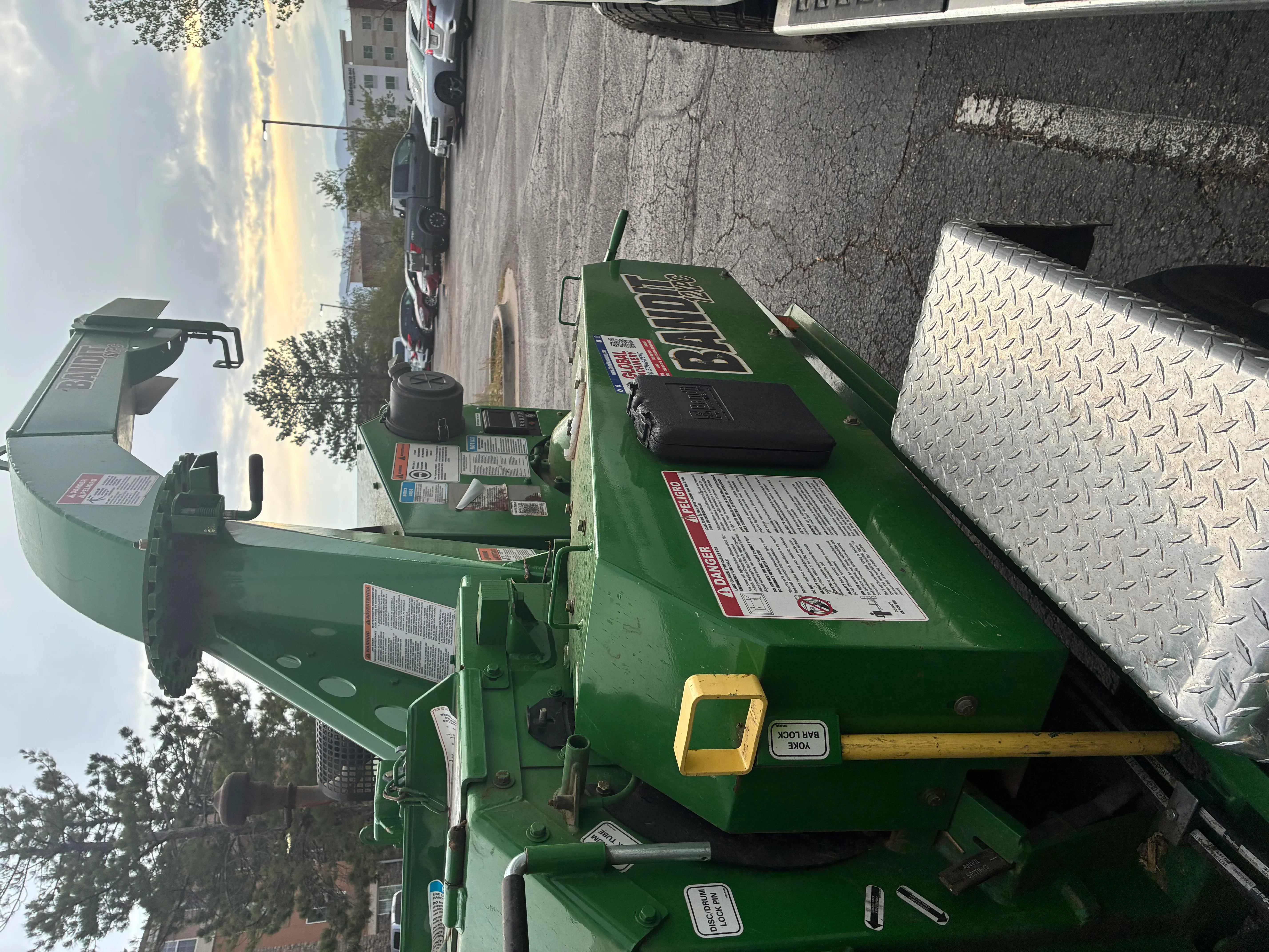 Green industrial wood chipper with diamond plate guards and safety controls