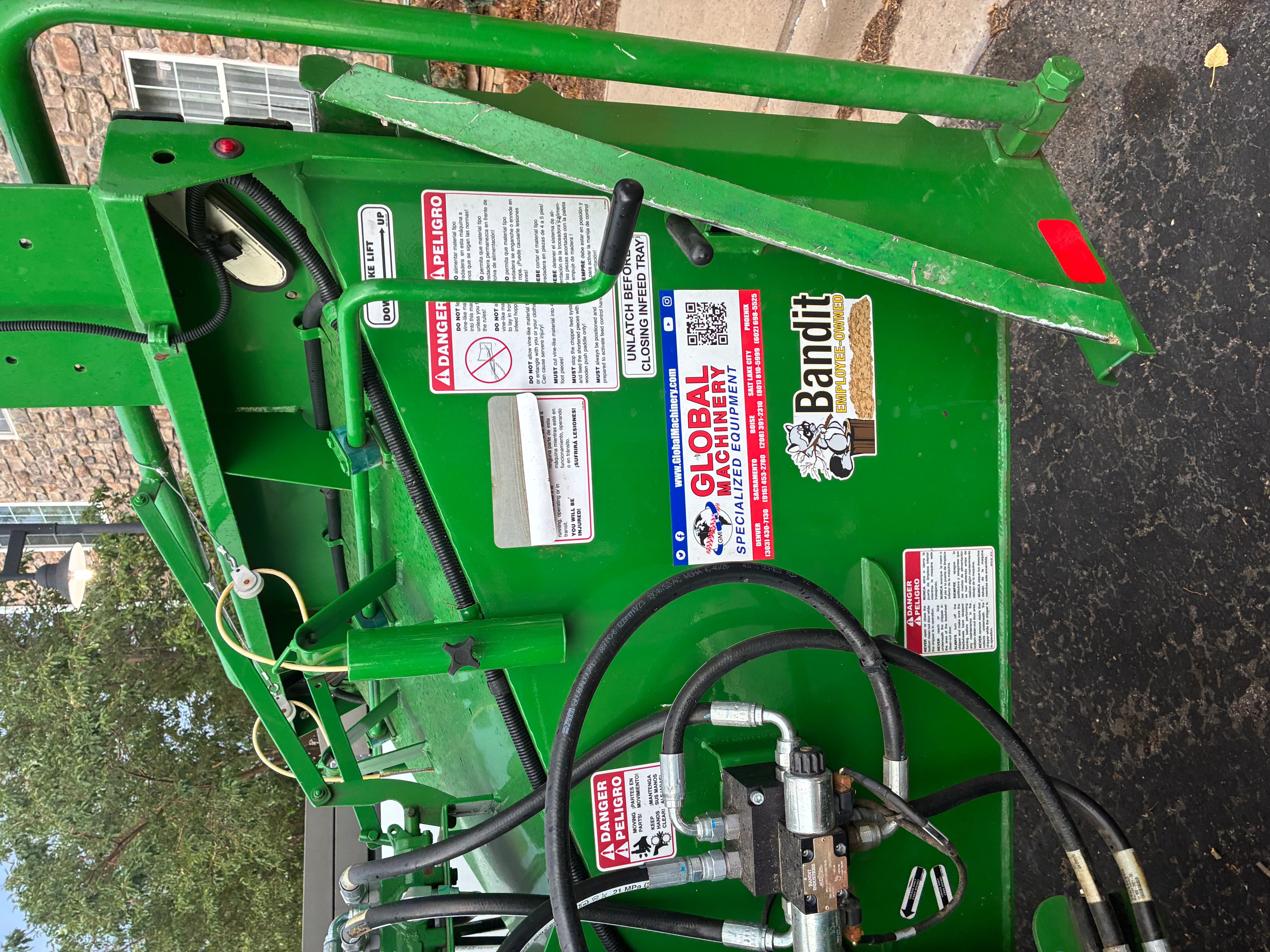 Green stump grinder with hydraulic hoses, safety labels, and operational controls