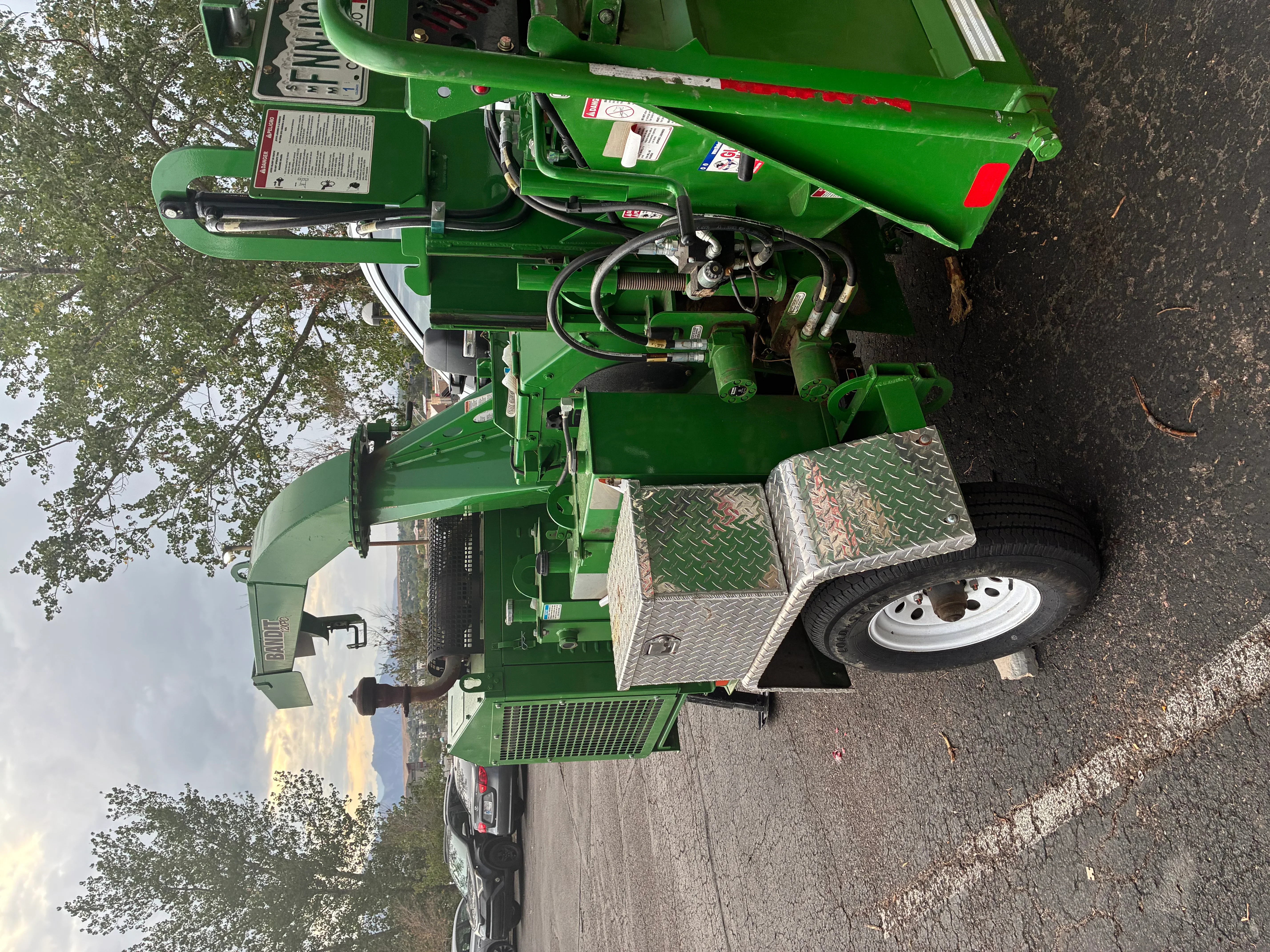 Green stump grinder trailer with hydraulic system, diamond plate deck, and engine components