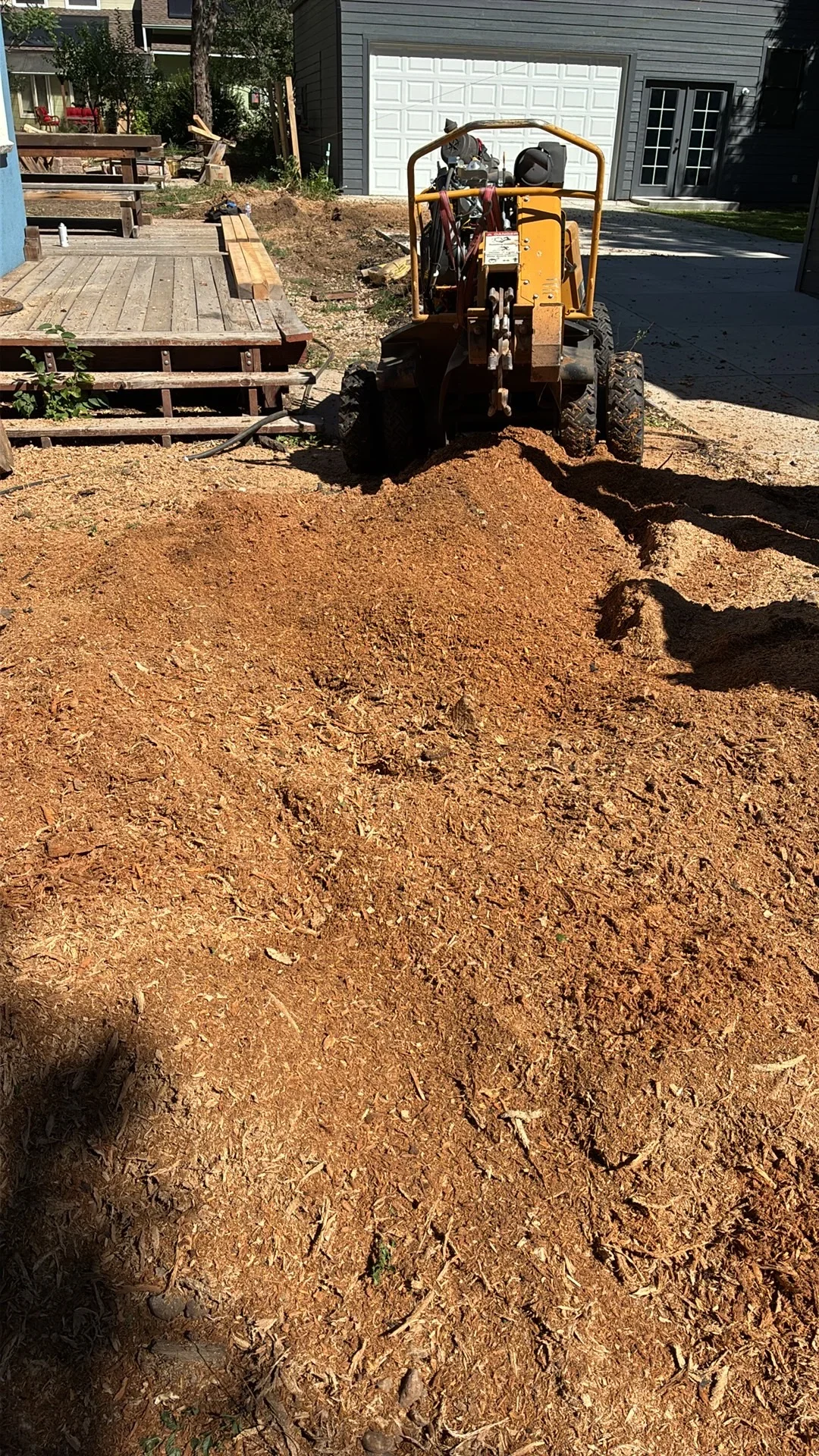 Walk-behind roller compactor grading compacted soil driveway base near residential garage