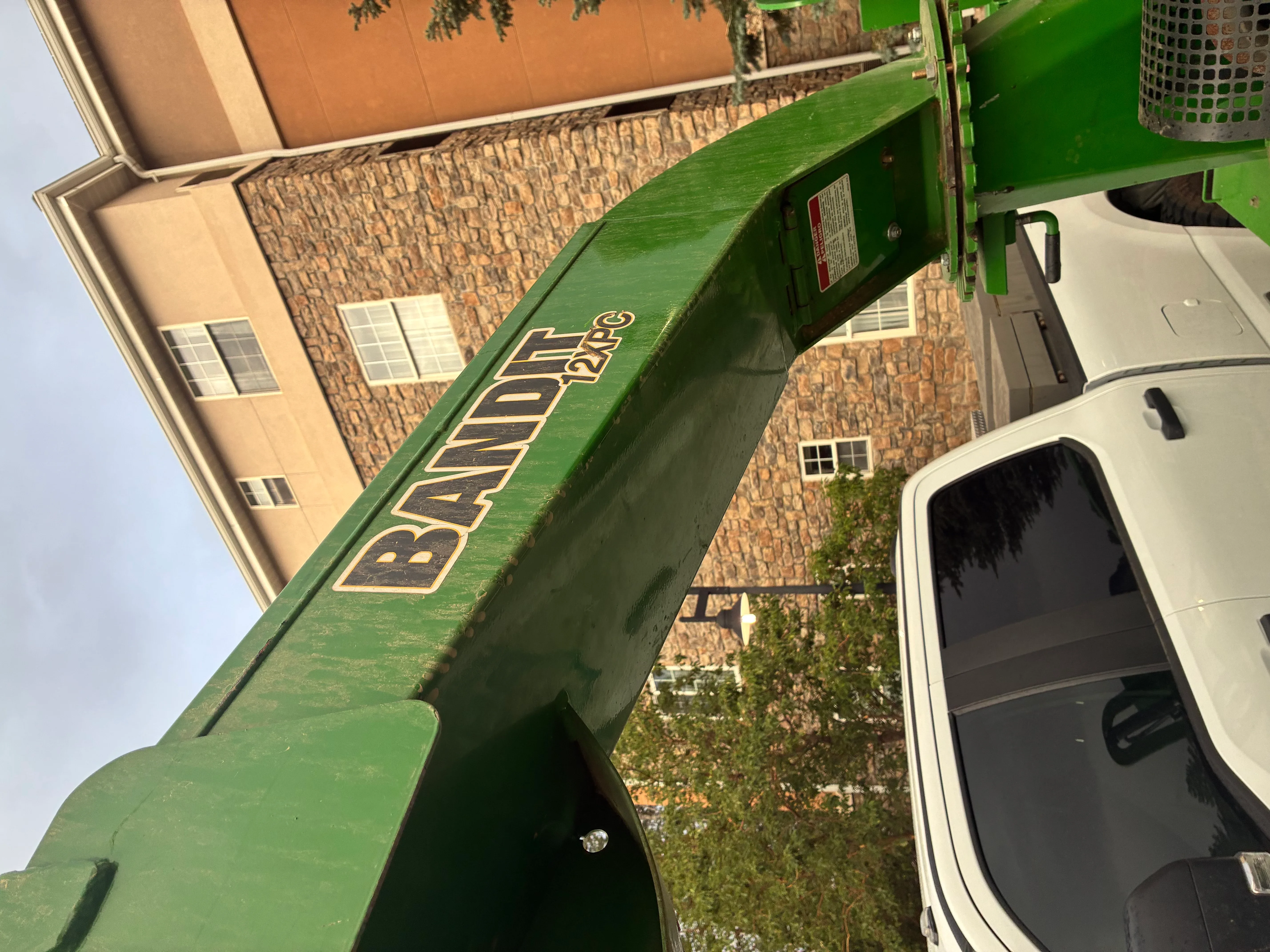 Green stump grinder with company branding on trailer bed