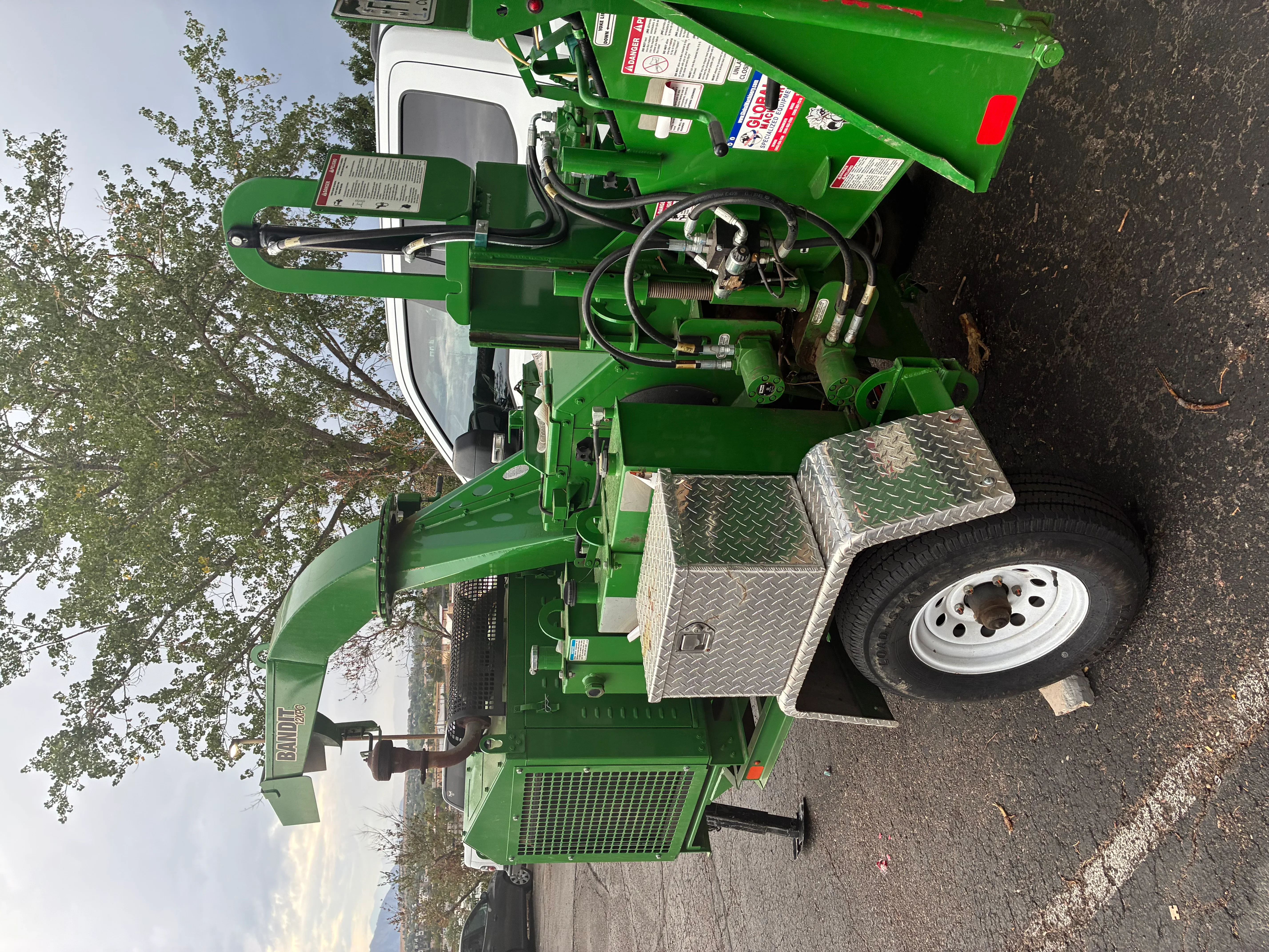 Green industrial wood chipper with hydraulic system and diamond plate platform