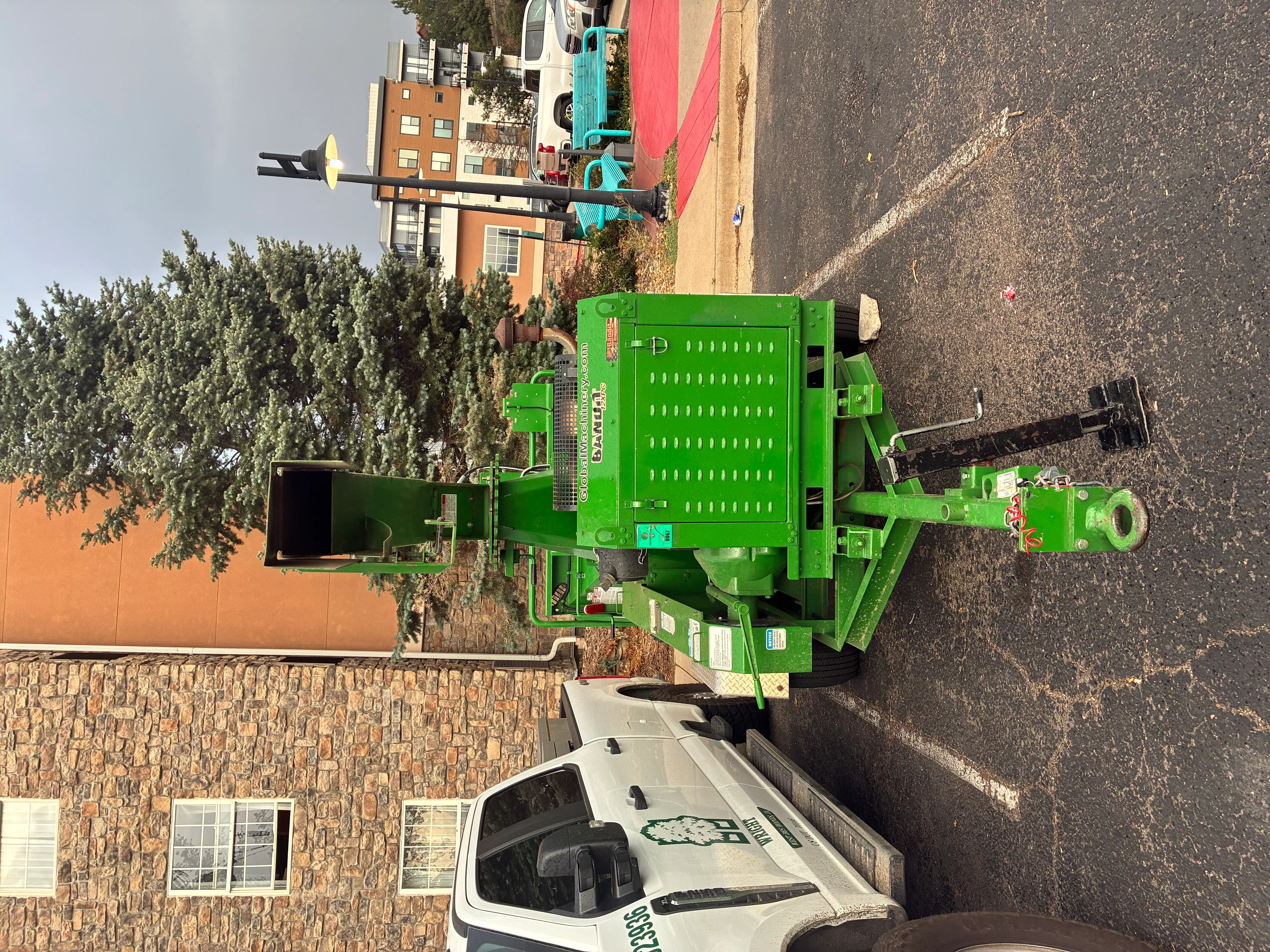 Green stump grinder with perforated hopper and hydraulic controls on residential driveway