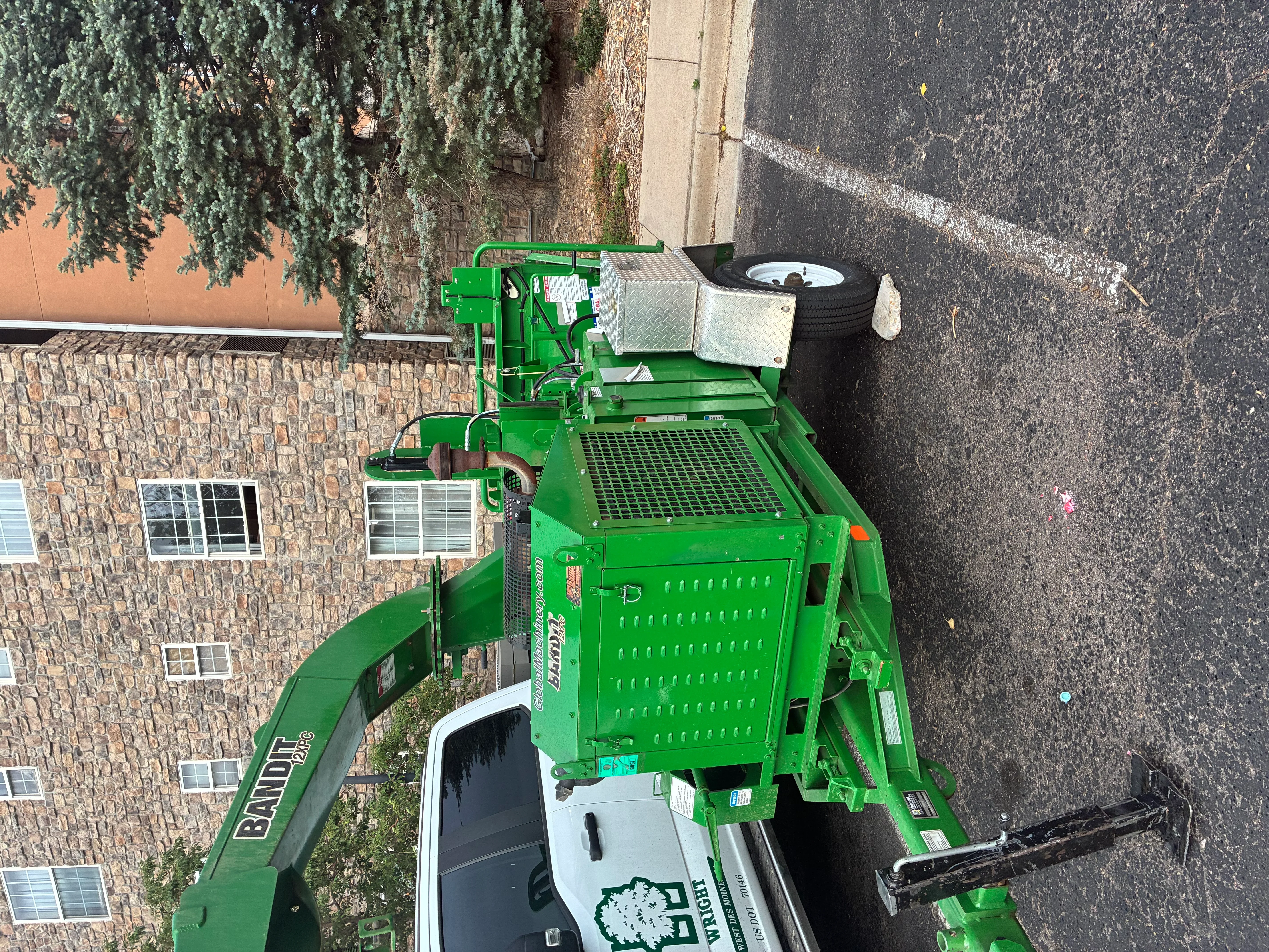 Green Vermeer stump grinder with metal platform and tire on residential driveway